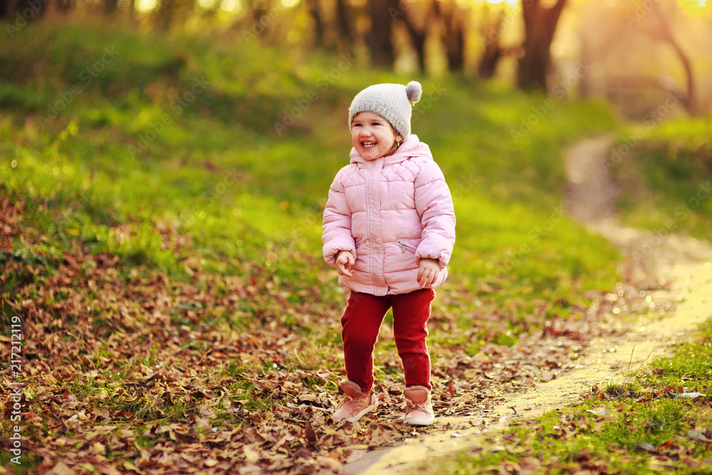 Portrait of beautiful happy child walking on autumn colorful leaves and grass background. Funny girl outdoors in fall park. Bright back light. Portrait of beautiful happy child walking on autumn colorful leaves and grass background. Funny girl outdoors in fall park. Bright back light.