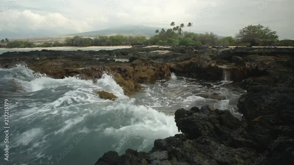 Waves crashing into the rugged shoreline of an old lava flow near a white sand beach in Hawaii. Waves crashing into the rugged shoreline of an old lava flow near a white sand beach in Hawaii.
