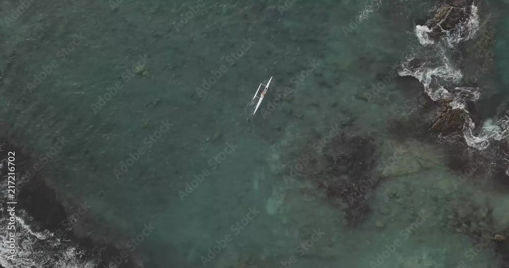 Person paddling an outrigger canoe off the coast of Hawaii