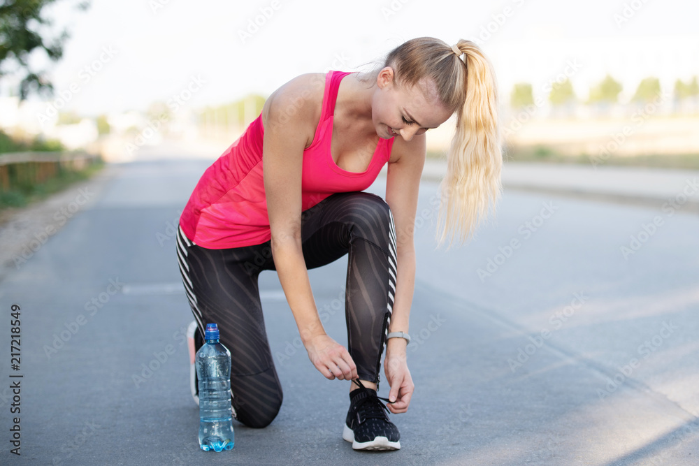 Sportliche junge Frau bindet ihre Laufschuhe Stock Photo | Adobe Stock