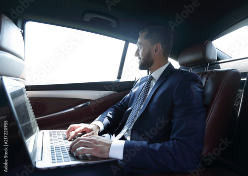 Businessman typing text on laptop while sitting in car © ASDF