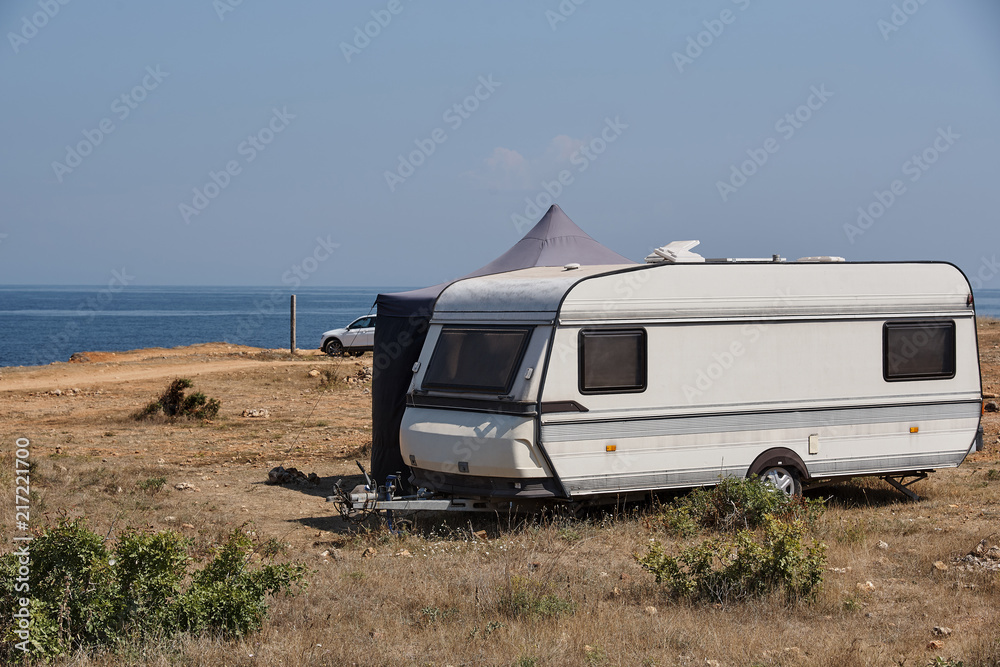 The house on wheels is parked on the beach in front of the blue sea in the wild The house on wheels is parked on the beach in front of the blue sea in the wild