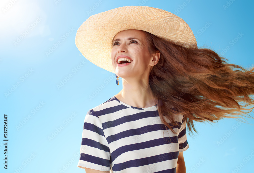 happy modern woman looking into distance against blue sky