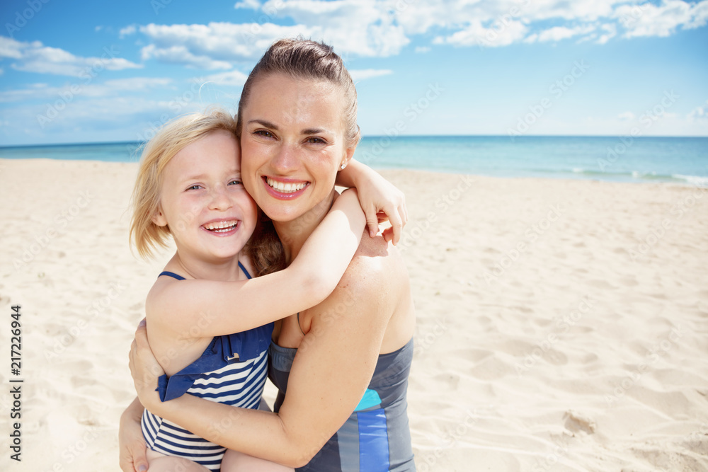 smiling young mother and child in beachwear on beach