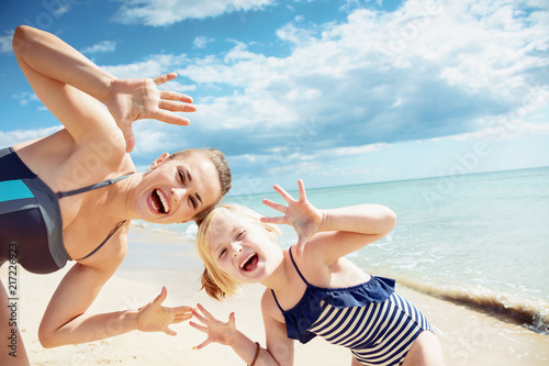 Fotografie smiling mother and daughter on seashore showing empty palms