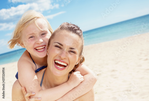 cheerful young mother and child in swimwear on seashore © Alliance