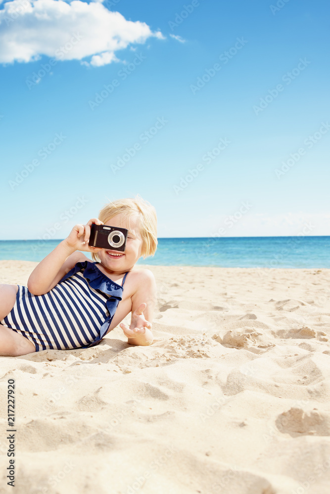 smiling girl in swimsuit taking photo with camera on beach smiling girl in swimsuit taking photo with camera on beach
