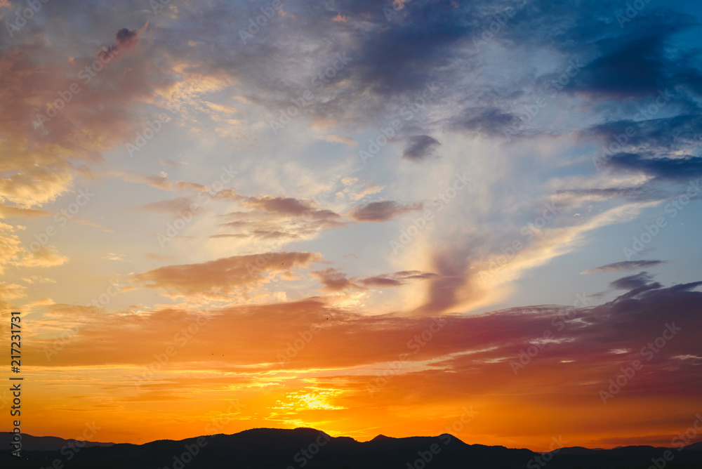 Beautiful sunset with the sun of orange tones behind the mountains and deep blue sky Beautiful sunset with the sun of orange tones behind the mountains and deep blue sky
