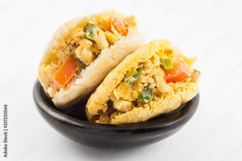 Arepas filled with scrambled eggs served in a black ceramic dish on white background Arepas filled with scrambled eggs served in a black ceramic dish on white background