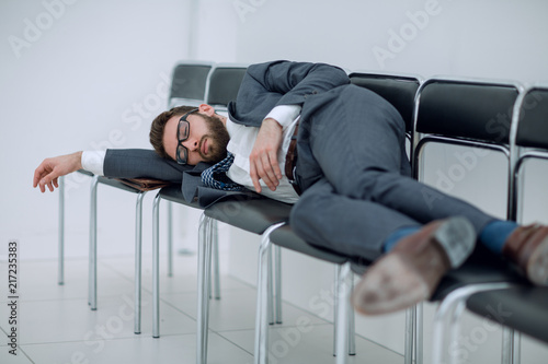 tired businessman lying on chairs and waiting for an interview
