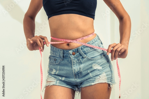 Photos Slim woman measures her waist with measuring tape.