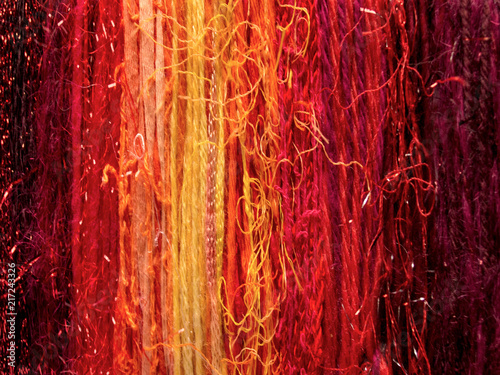 Vertical striped background composed of varying colors and textures of yarns, creating color sequences from left to right.