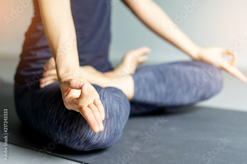 Young woman practicing yoga in gray background.Young people do yoga indoor.Close up hands in meditating gesture. Copy space.