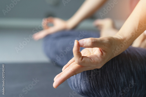 Young woman practicing yoga in gray background.Young people do yoga indoor.Close up hands in meditating gesture. Copy space.