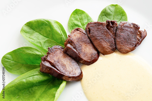 turkey hearts appetizer with spinach leafs and gravy sauce