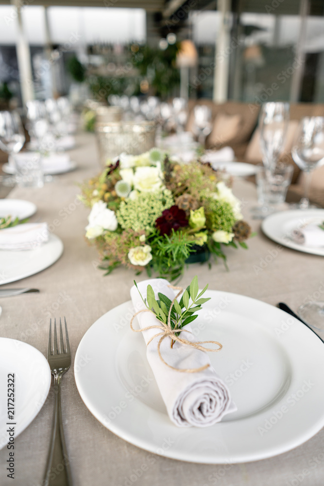Neatly twisted into a tube dining room napkin decorated with a sprig of pistachio. Wedding Banquet or gala dinner. The chairs and table for guests, served with cutlery and crockery. party on terrace Neatly twisted into a tube dining room napkin decorated with a sprig of pistachio. Wedding Banquet or gala dinner. The chairs and table for guests, served with cutlery and crockery. party on terrace