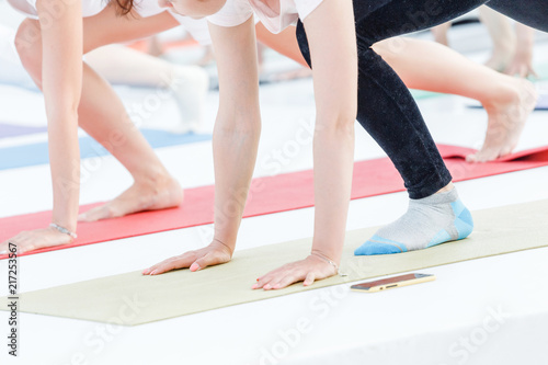 Young sporty woman practicing yoga at class, doing stretching exercise. Close-up detail view of leg and hand photo