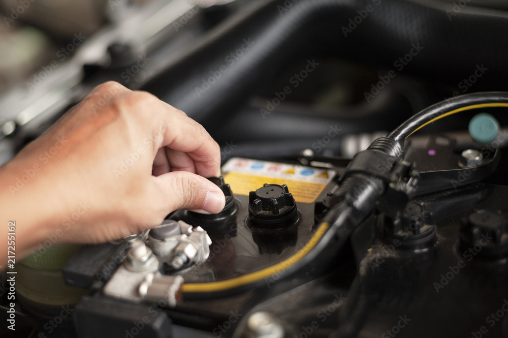Hands of mechanic working in auto repair shop Add distilled water in battery. Hands of mechanic working in auto repair shop Add distilled water in battery.