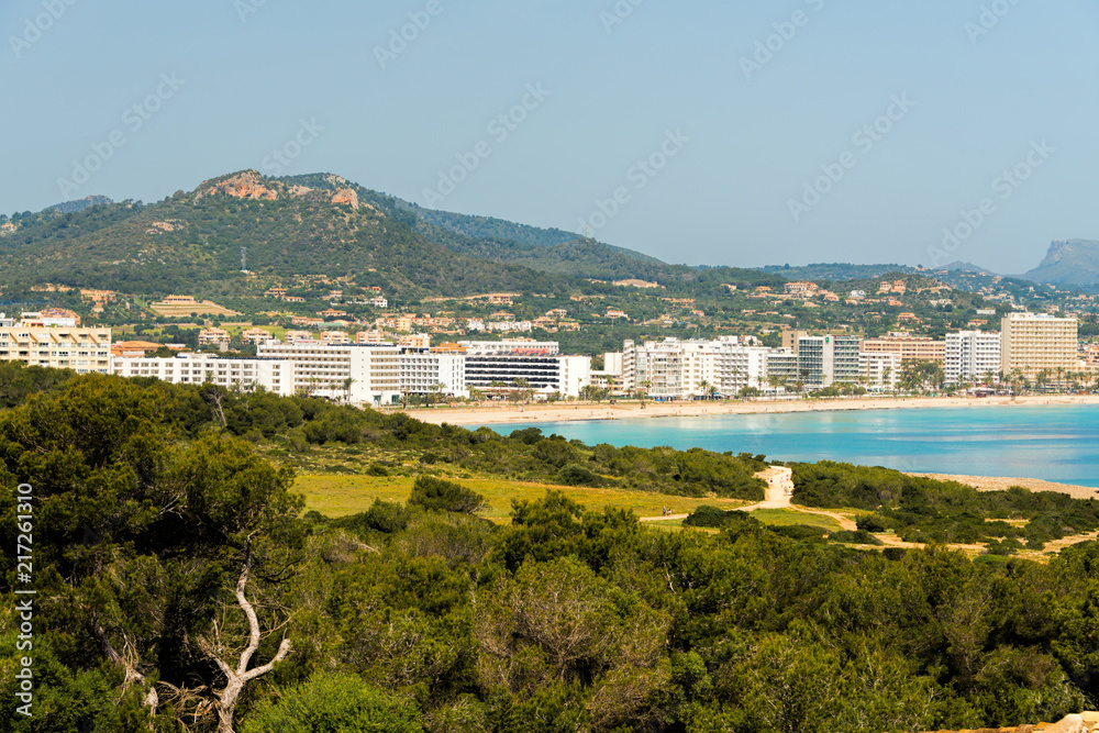 Obraz premium View to the beach of Cala Millor with the hotels and beach promenade with the hills and mountains in the background on the Spanish Mediterranean island Mallocra