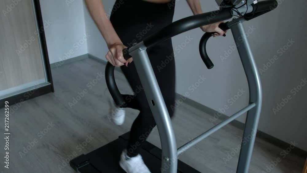 Young Woman Exercising on treadmill at Home. Sport woman is engaged in sports at home. Home fitness.