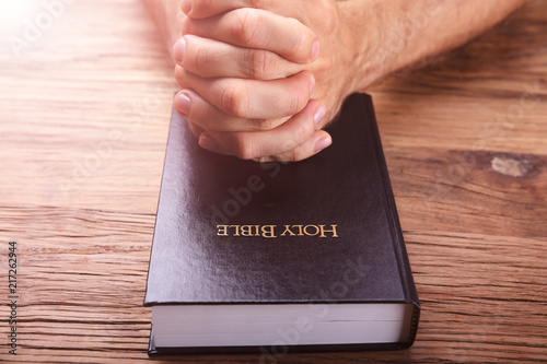 Man's Praying Hands On Bible
