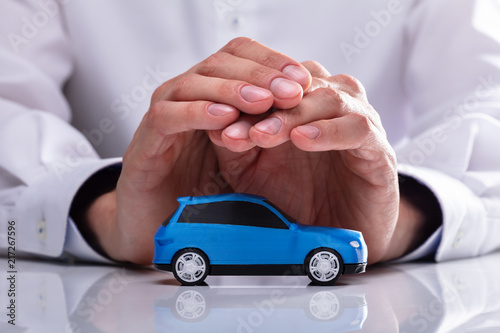 Foto Businessman Protecting Blue Car