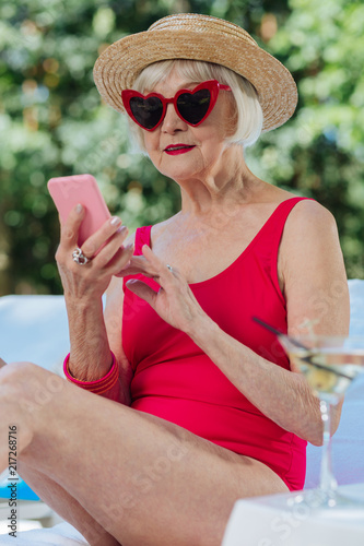 Mature woman. Blonde-haired mature woman wearing fashionable bright red swimming suit sunbathing