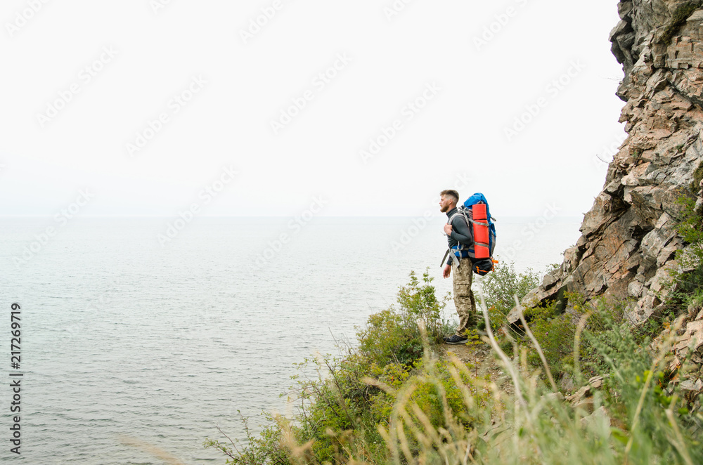 Young guy tourist with backpack on lake and mountains background Young guy tourist with backpack on lake and mountains background