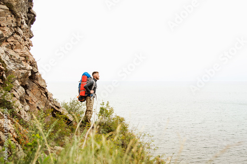 Young guy tourist with backpack on lake and mountains background © vika33