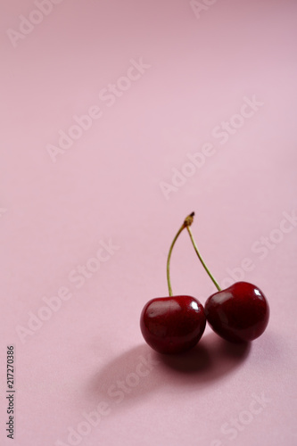 Two cherries on pink