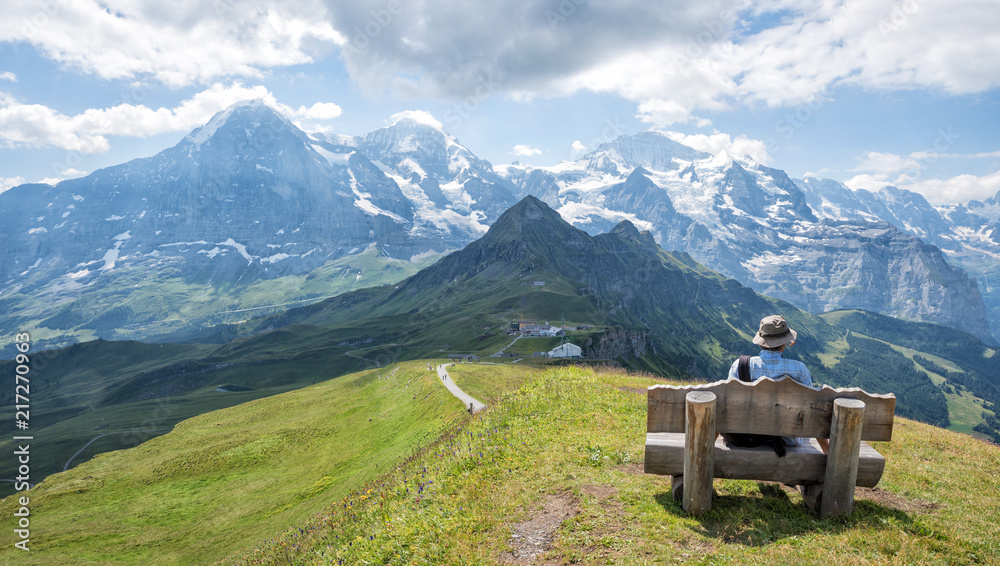 Wanderer auf der Rastbank, genießt die atemberaubende Aussicht auf die Schweizer Alpen