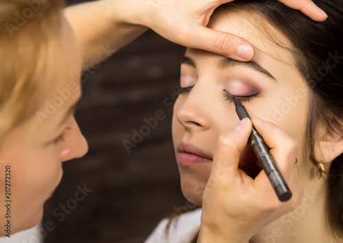 Make-up artist applying liquid eyeliner with brush to beautiful woman face. Make up in process