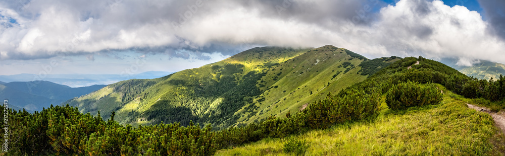Obraz premium Panoramic view from summer mountains under cloudy sky