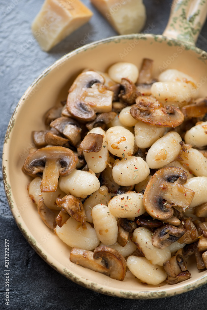 Above view of a serving pan with gnocchi and fried champignons, vertical shot, closeup Above view of a serving pan with gnocchi and fried champignons, vertical shot, closeup