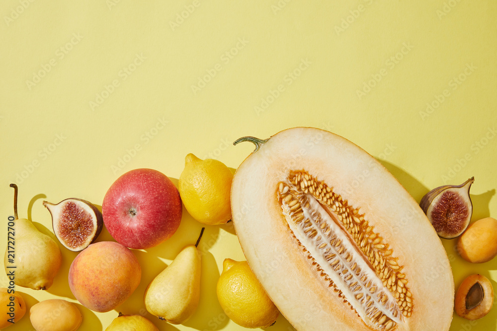 Φωτογραφία top view of halved melon and fresh ripe fruits on yellow background