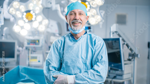 Portrait of the Professional Surgeon Looking Into Camera and Smiling after Successful Operation. In the Background Modern Hospital Operating Room.