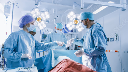 Фотография Shot of Diverse Team of Professional Surgeons Performing Invasive Surgery on a Patient in the Hospital Operating Room