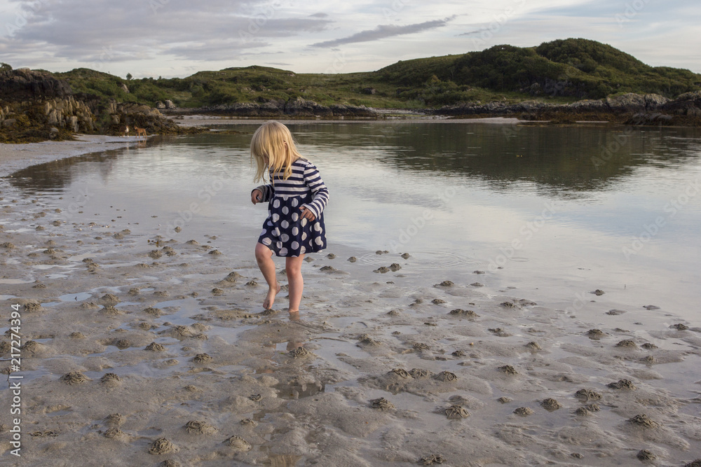 Young girl playing on a sandy beach in Scotland on a sunny day Young girl playing on a sandy beach in Scotland on a sunny day
