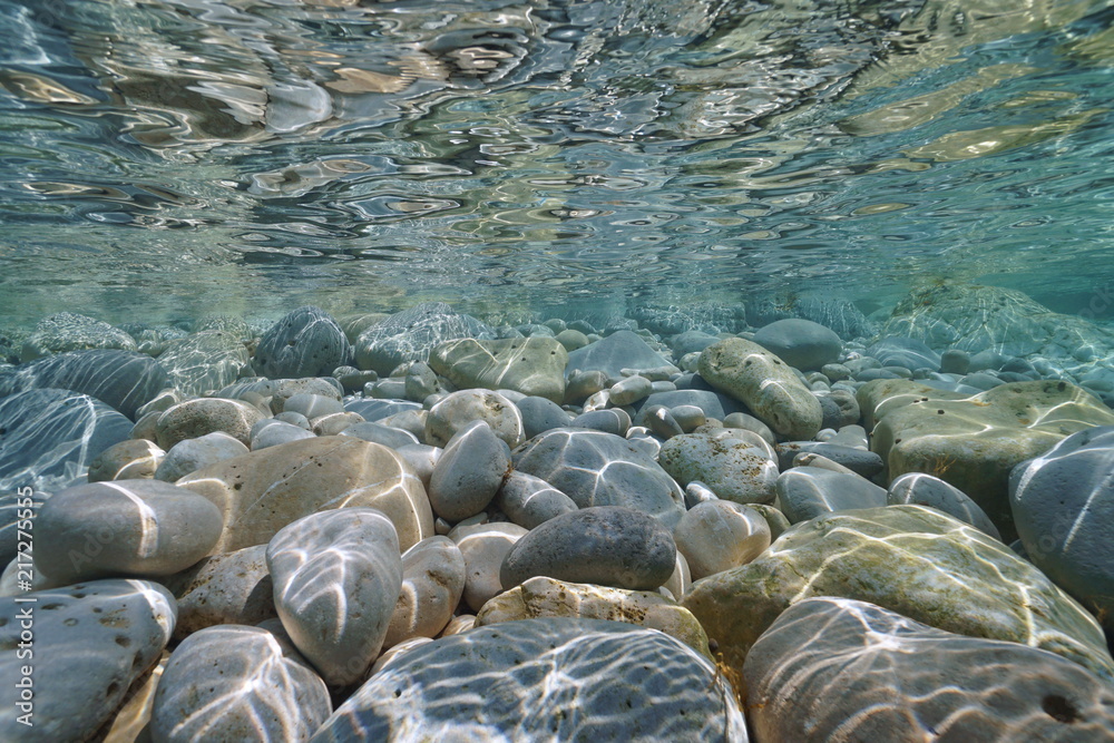 Underwater pebbles and rocks below water surface on the seashore, Mediterranean sea, Costa Blanca, Javea, Alicante, Valencia, Spain - obrazy, fototapety, plakaty 
