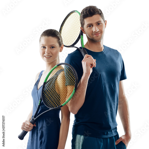 Portrait of tennis players, isolated on white. Young man and woman holding a racquets, giving a slight smile. © yuriygolub