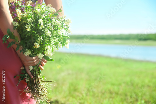 Young woman holding bouquet of beautiful flowers outdoors