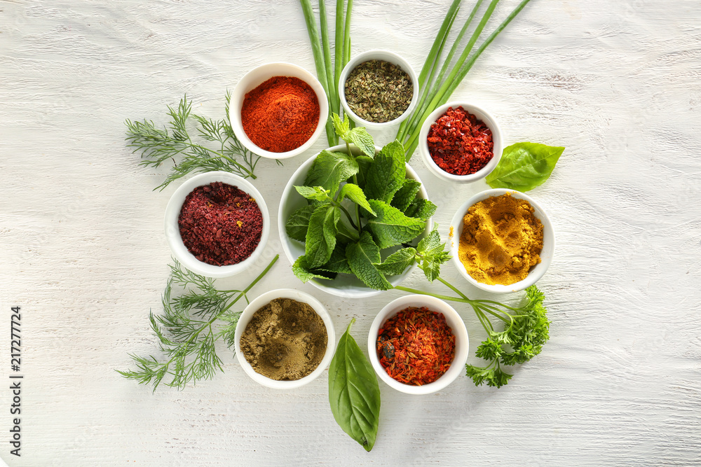 Composition with different spices and herbs on white wooden background