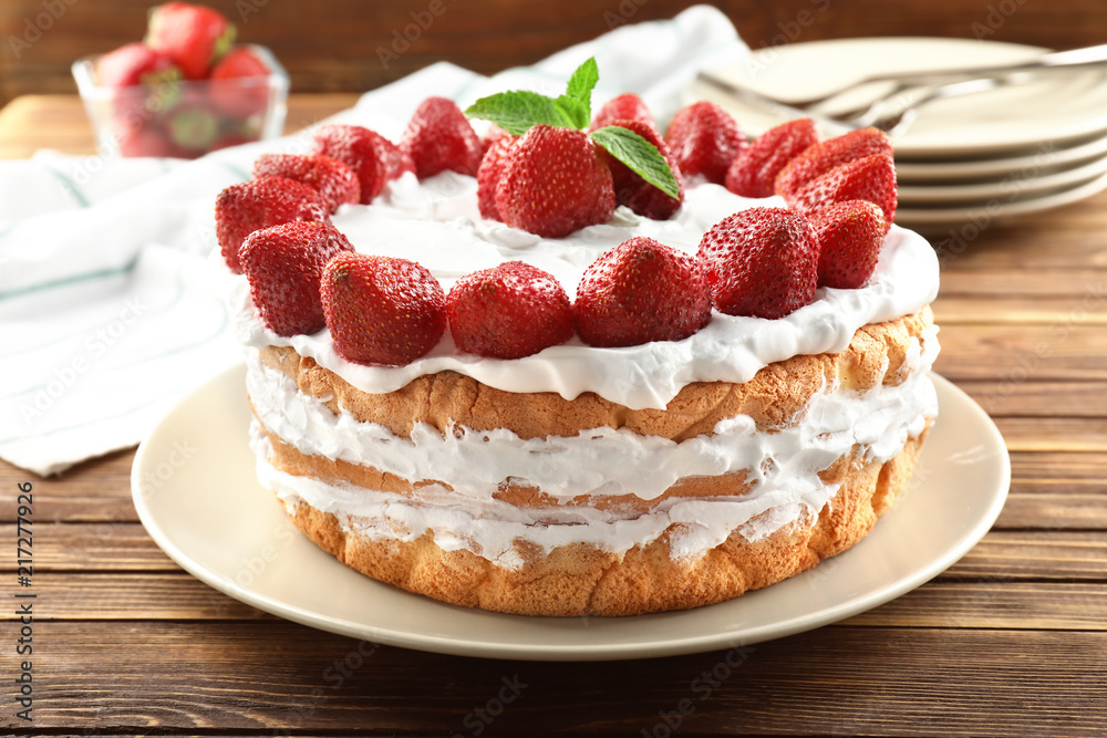 Delicious cake with strawberries on wooden table