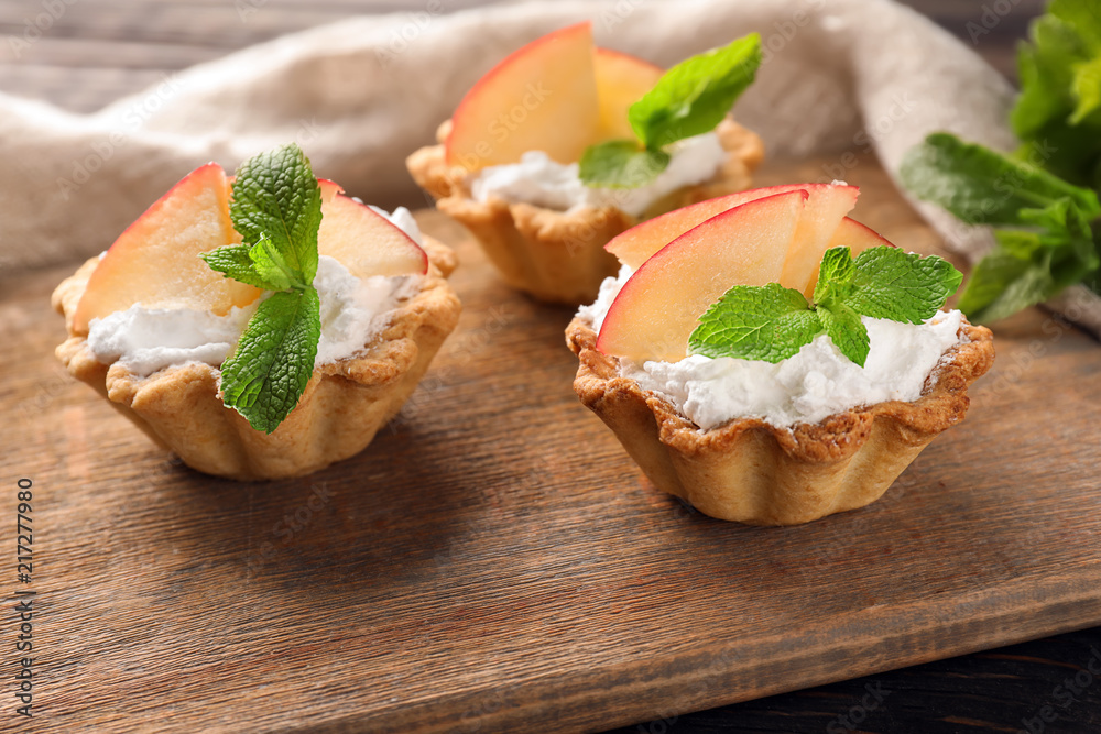 Delicious tartlets with cream and fruit on wooden board Delicious tartlets with cream and fruit on wooden board