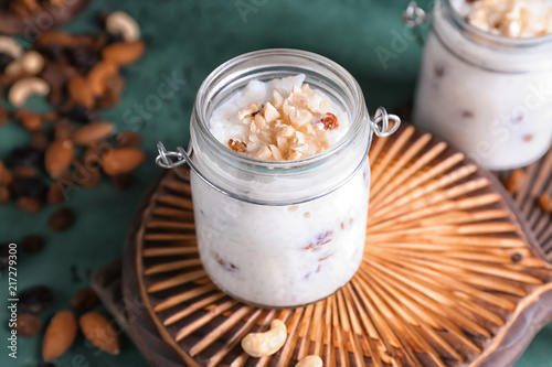 Glass jar with delicious rice pudding and nuts on board, closeup