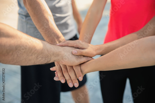Group of sporty people putting hands together outdoors  closeup