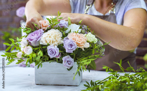 Obraz na plátně timelapse professional florist arranging flower composition in wooden box in floral design studio