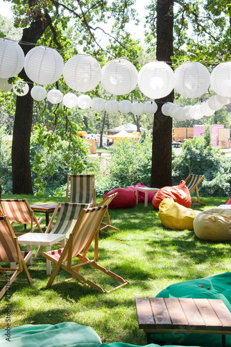 Summer cafe in the park. Paper lanterns, tables and chairs are bags. Bright environment. sunny day