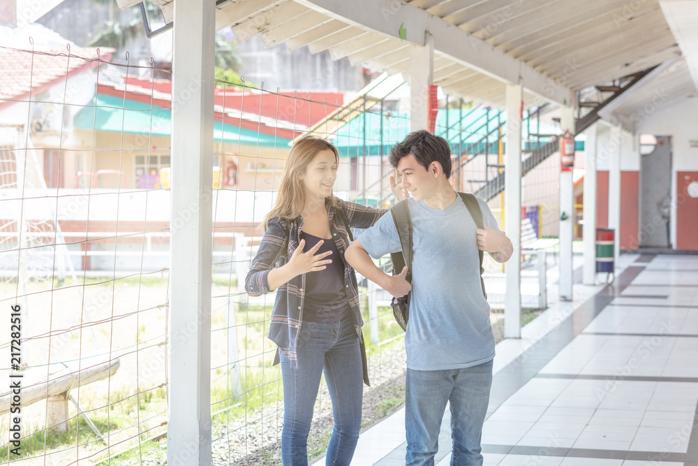 Couple of teenagers happy in school hallway, sun rays coming from the sky