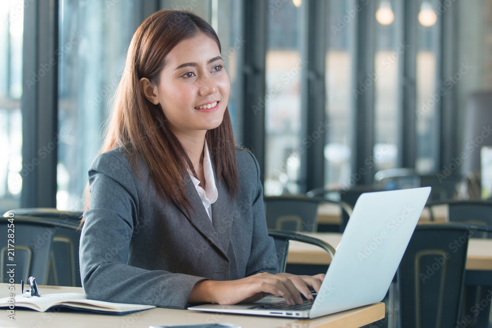 Portrait of an professional investment advisor businesswoman sitting in front of laptop at her desk while looking at camera and smiling. Portrait of an professional investment advisor businesswoman sitting in front of laptop at her desk while looking at camera and smiling.